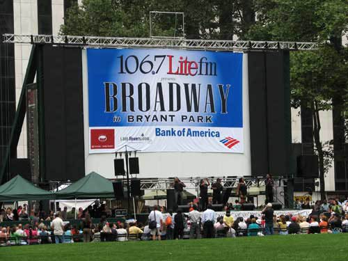 Bryant Park people on grass big stage with 106.7 lite fm Broadway in Bryant Park